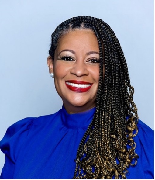 Smiling woman with long braids in blue shirt.